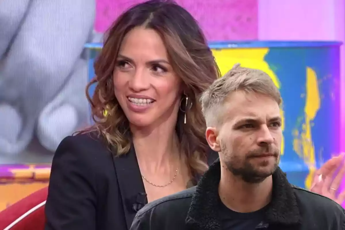 Una mujer sonriente con brackets y un hombre con barba y chaqueta oscura frente a un fondo colorido.