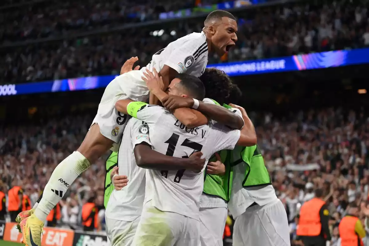 Jugadores de fútbol celebrando un gol en un estadio lleno de espectadores.