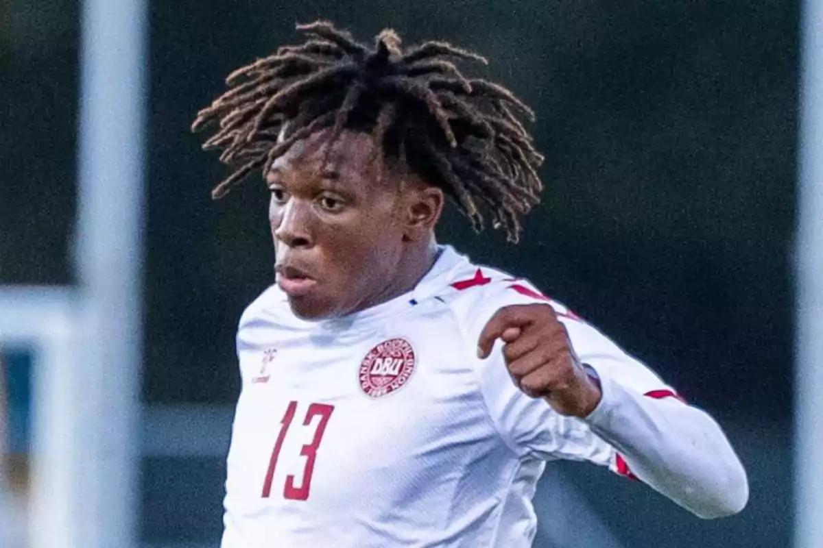 Un jugador de fútbol con el uniforme blanco de la selección de Dinamarca, con el número 13 en el pecho, en acción durante un partido. Un jugador de fútbol con el uniforme blanco de la selección de Dinamarca, con el número 13 en el pecho, en acción durante un partido.