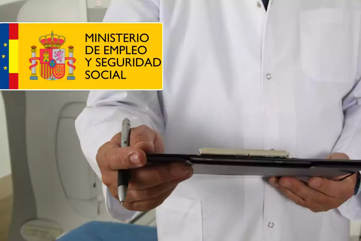 Un médico con bata blanca sostiene una carpeta con una mano y un bolígrafo con la otra, junto a un cartel del Ministerio de Empleo y Seguridad Social de España.