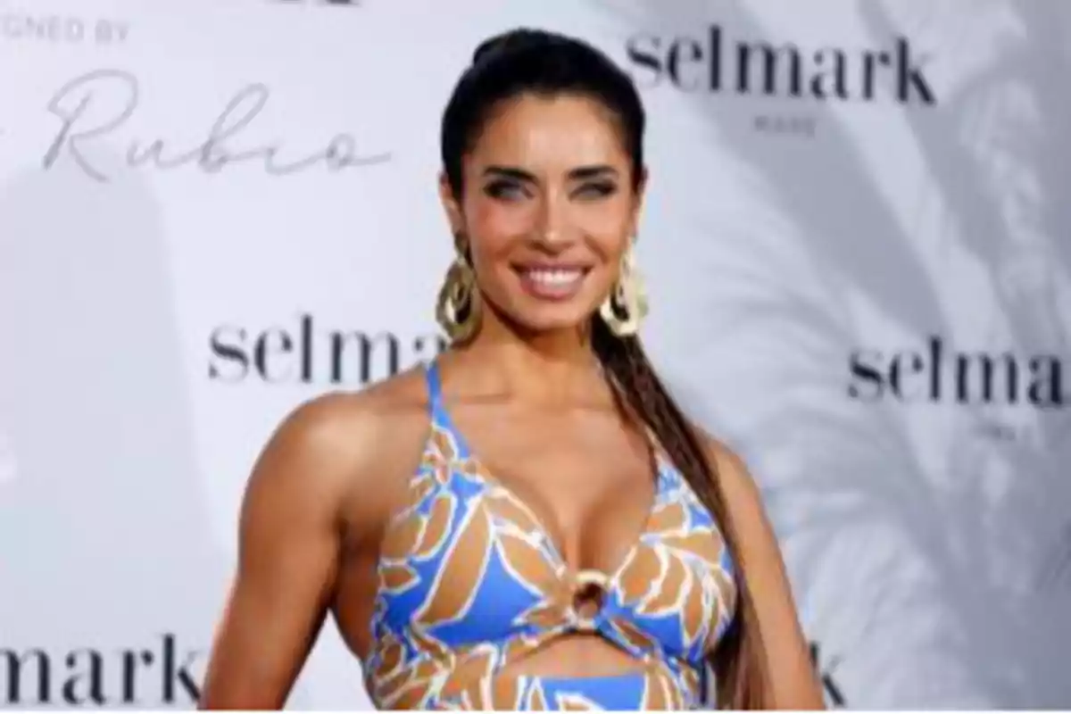 Una persona sonriendo con un vestido de estampado azul y marrón en un evento de moda. Una persona sonriendo con un vestido de estampado azul y marrón en un evento de moda.