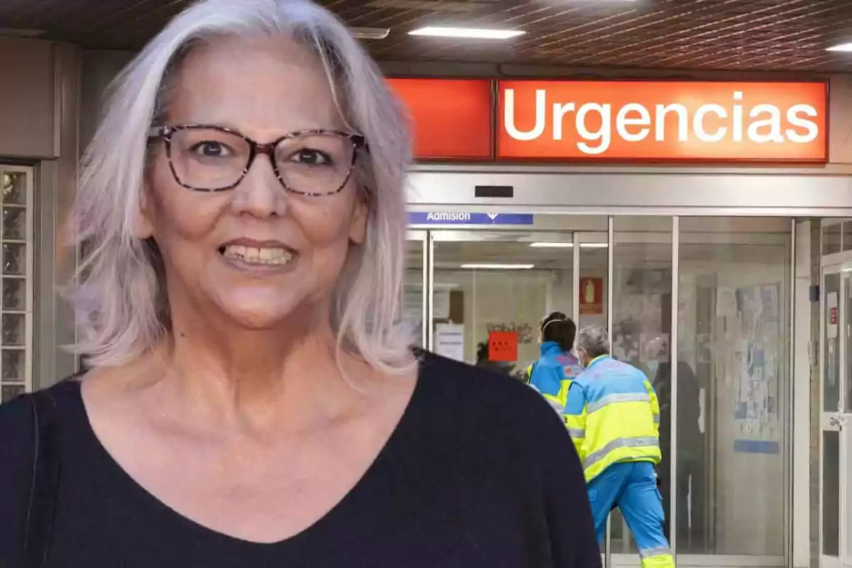 Una mujer con gafas sonríe frente a la entrada de urgencias de un hospital.