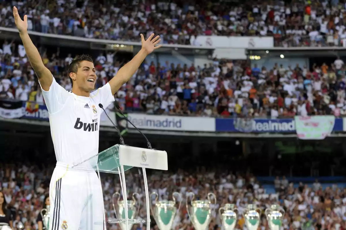 Imagen de la presentación de Cristiano Ronaldo con el Real Madrid, el jugador vestido con la equipación tiene los brazos en alto y de fondo los trofeos del club y las gradas llenas Imagen de la presentación de Cristiano Ronaldo con el Real Madrid, el jugador vestido con la equipación tiene los brazos en alto y de fondo los trofeos del club y las gradas llenas