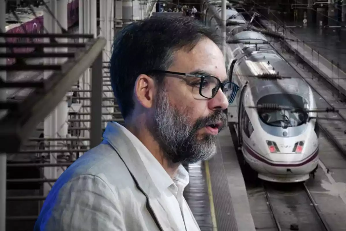 Un hombre con barba y gafas está en una estación de trenes de alta velocidad.