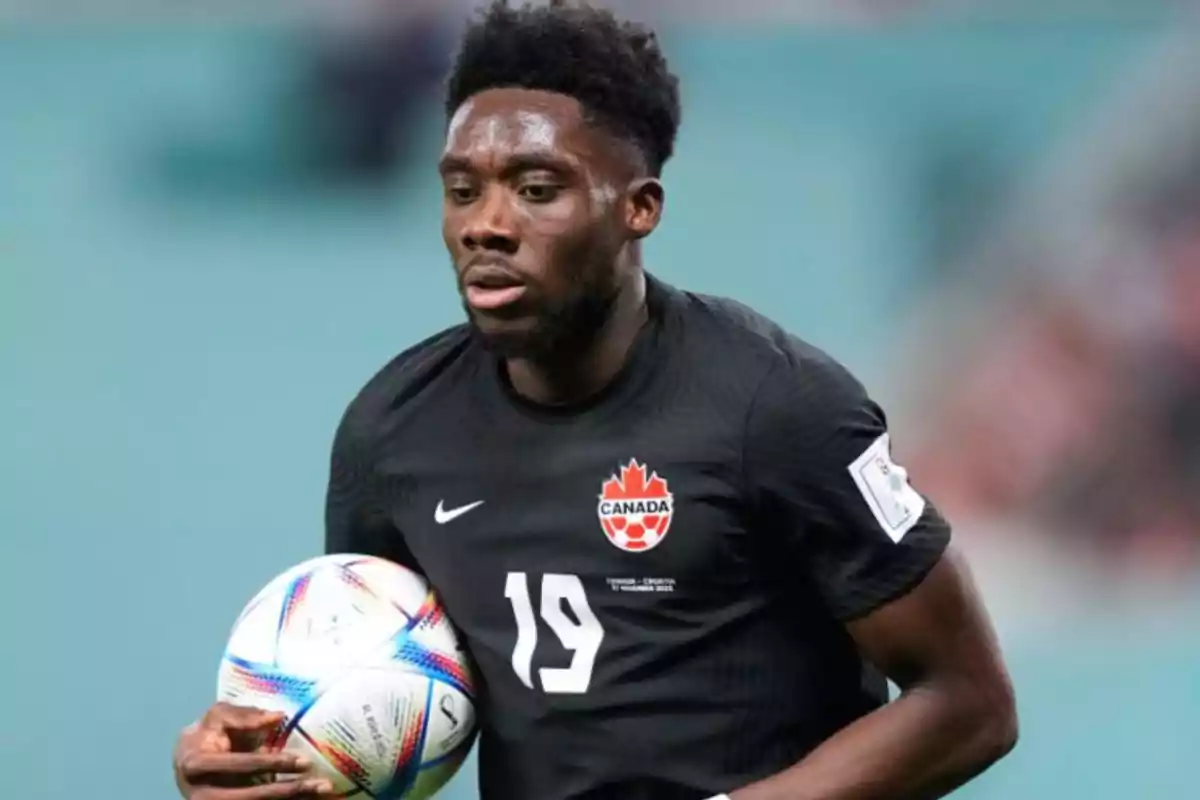 Jugador de fútbol de la selección de Canadá sosteniendo un balón durante un partido.