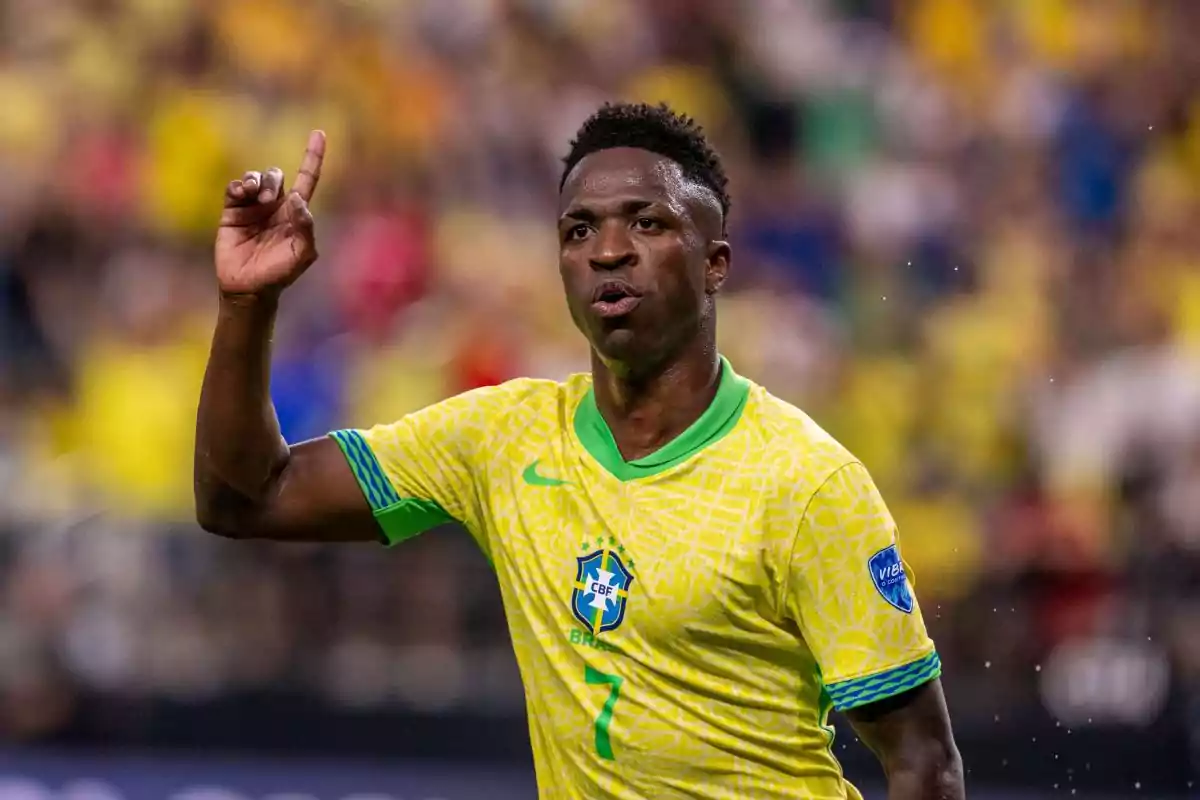 Vinicius Júnior con uniforme amarillo y verde de la selección de Brasil levantando un dedo durante un partido.