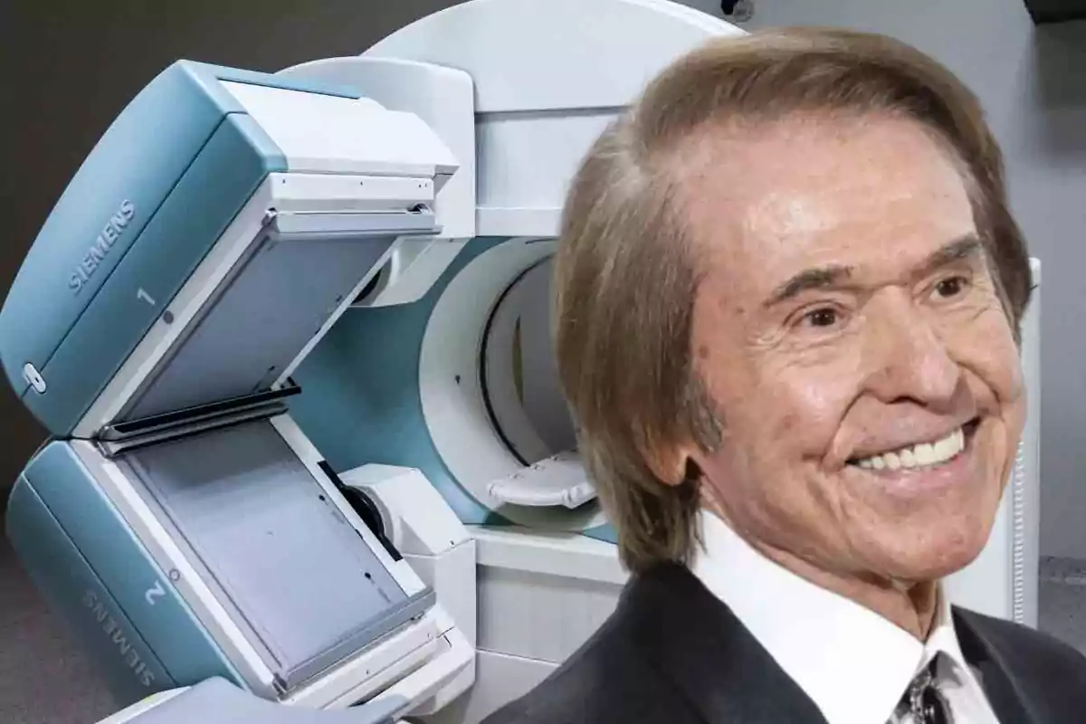 Un hombre sonriente con cabello castaño claro y un traje oscuro está frente a una máquina médica de la marca Siemens.