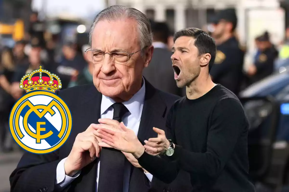 Un hombre mayor con gafas y traje oscuro está de pie junto al escudo del Real Madrid mientras otro hombre más joven con suéter oscuro parece estar hablando o gritando en un entorno urbano.