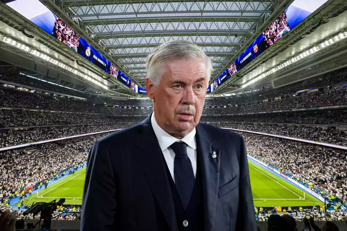 Un hombre de traje en un estadio de fútbol lleno de espectadores.