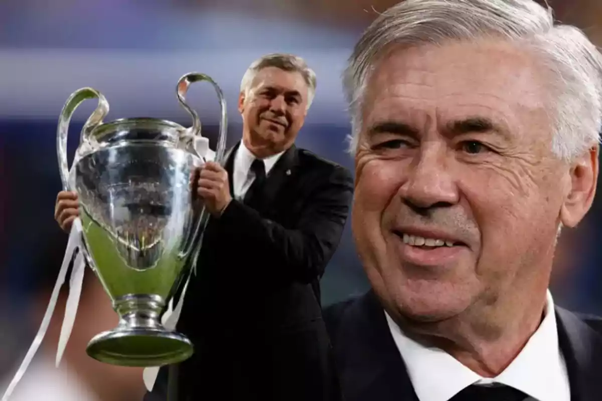 Un hombre sonriente con cabello canoso y traje oscuro sostiene un gran trofeo plateado con asas.