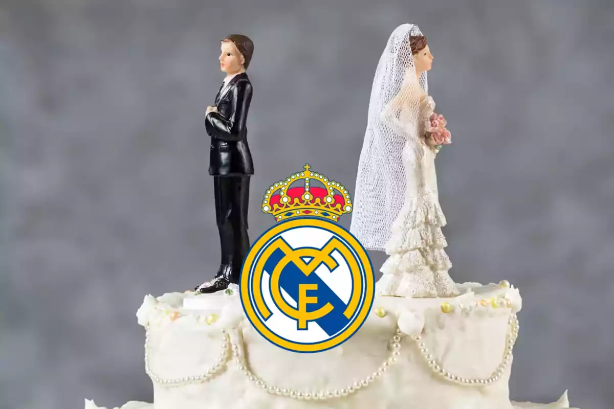 Figura de pastel de boda con novios de espaldas y un escudo del Real Madrid en el centro.