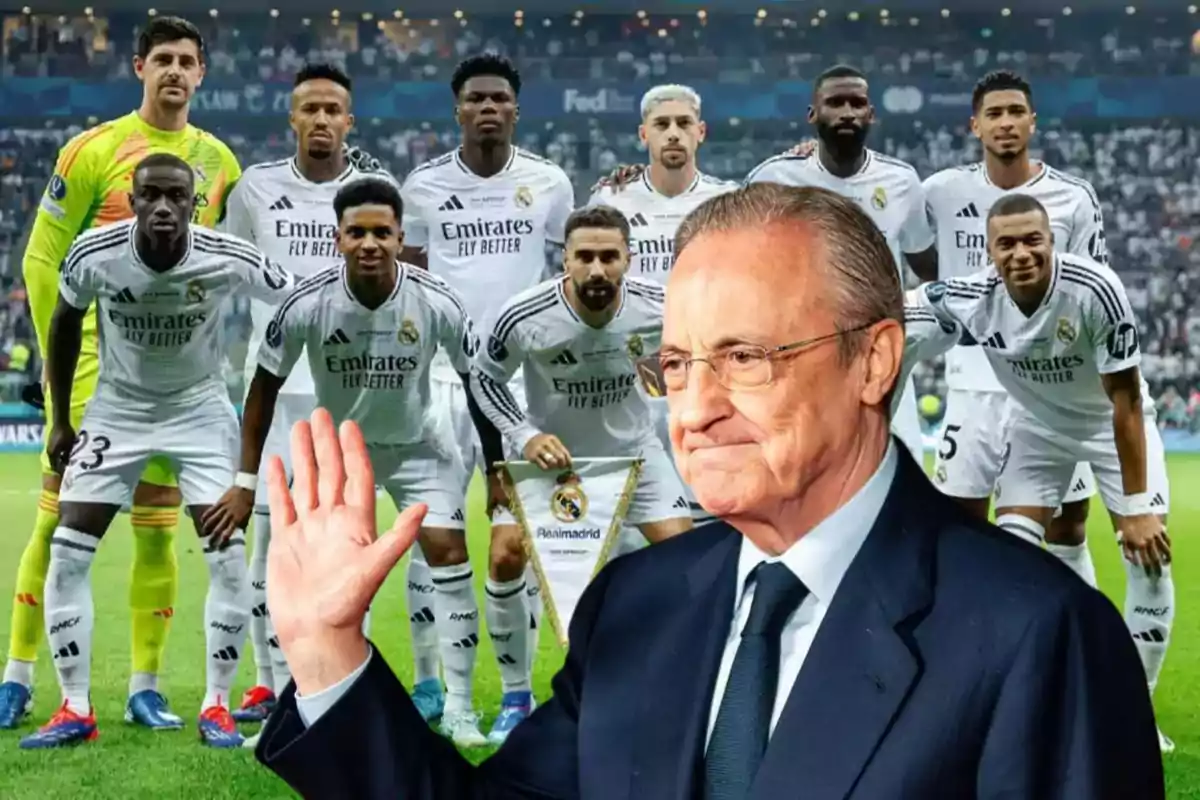 Un grupo de jugadores de fútbol con uniforme blanco posando en el campo, con un hombre en traje al frente levantando la mano.