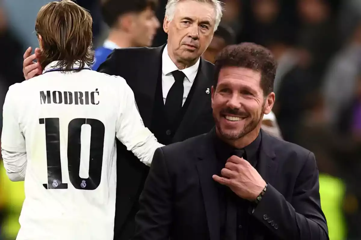 Un jugador de fútbol con el número 10 en su camiseta está de espaldas, mientras un hombre de traje oscuro está detrás de él y otro hombre sonriente con traje negro está en primer plano.