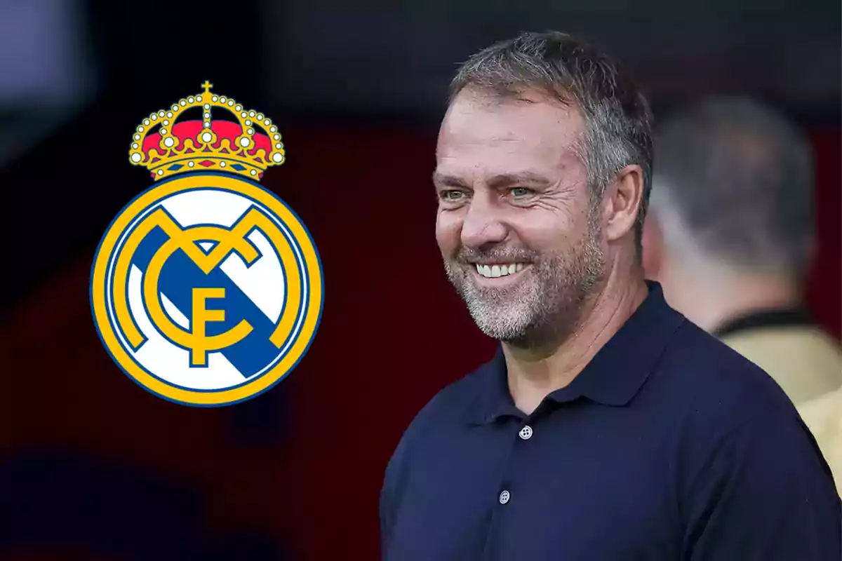 Un hombre sonriente con una camisa oscura junto al escudo del Real Madrid.