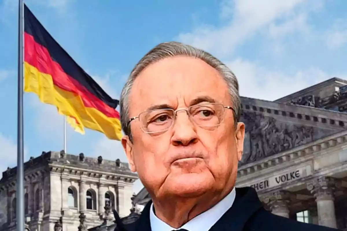 Un hombre con gafas frente a un edificio histórico y una bandera de Alemania ondeando en el fondo.