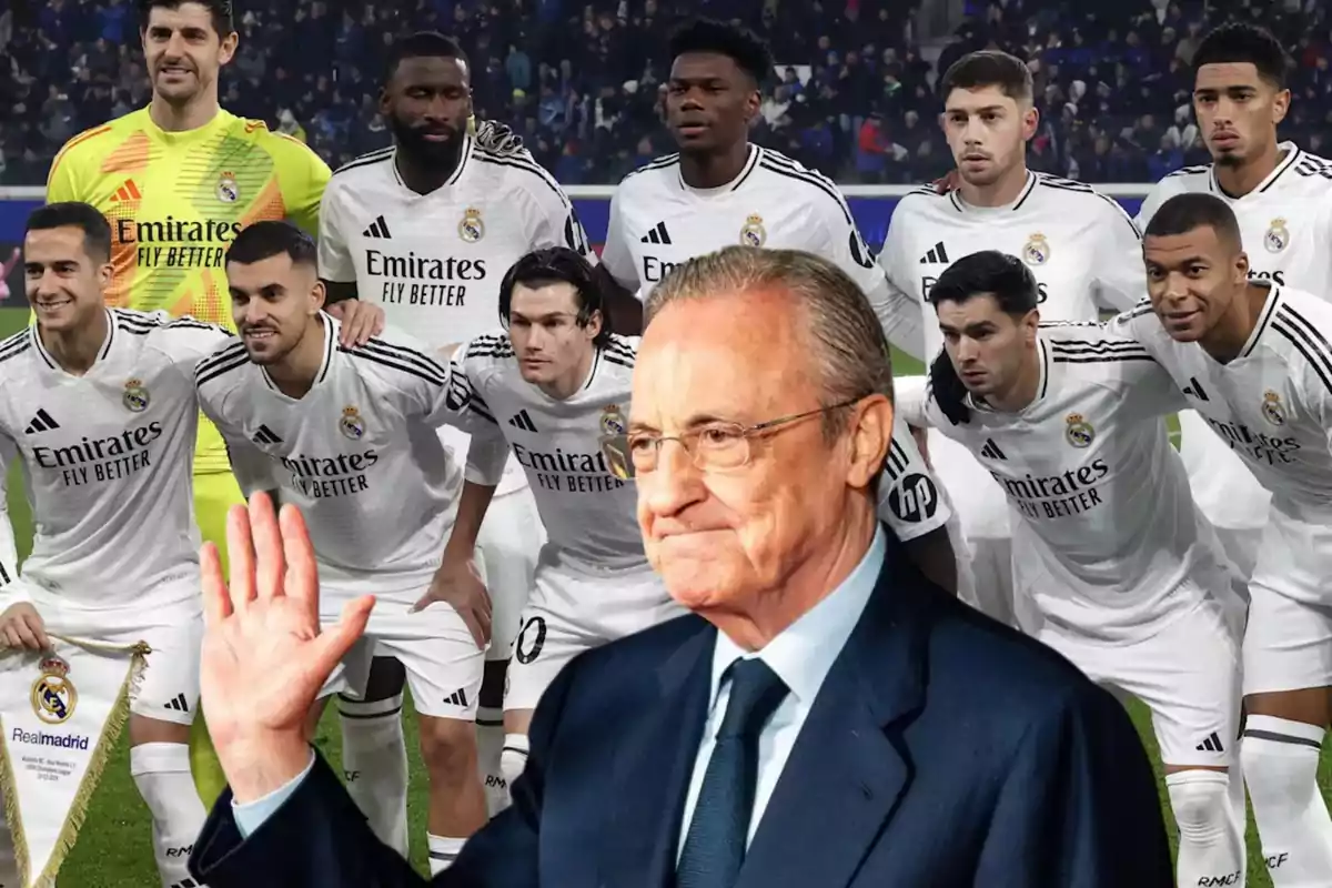 Un grupo de jugadores de fútbol con uniformes blancos posando en el campo, con un hombre en traje al frente levantando la mano.