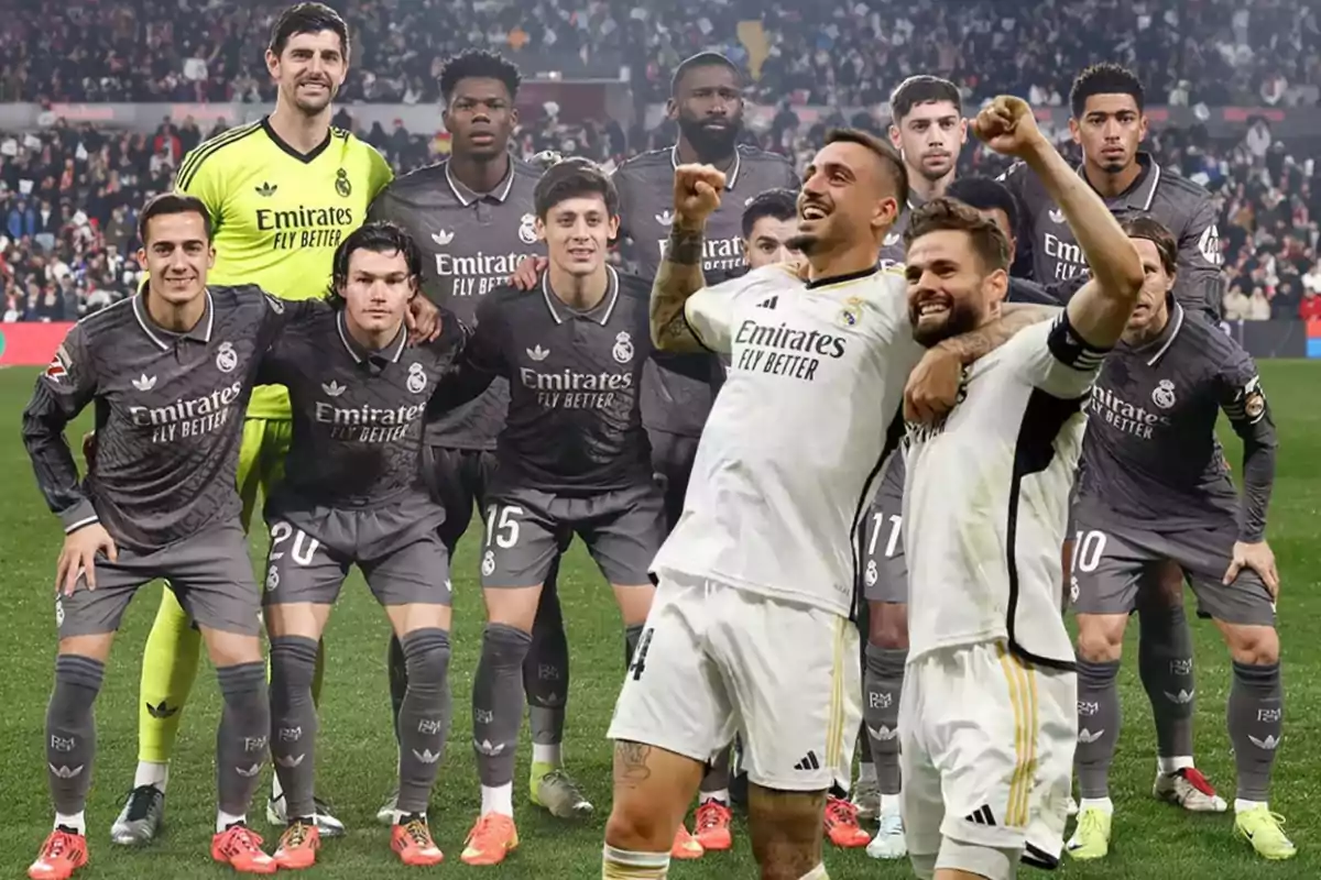 Jugadores de un equipo de fútbol posando en el campo, algunos con uniforme gris y otros celebrando con uniforme blanco.