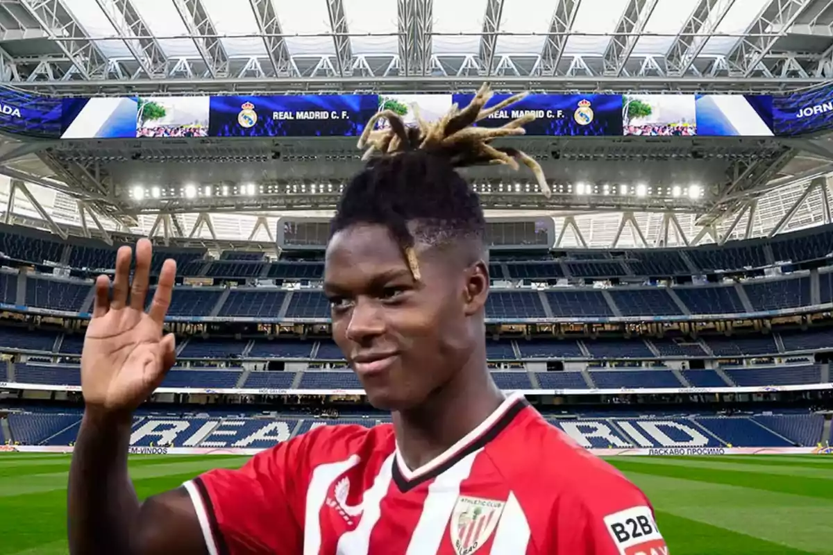 Un jugador de fútbol con la camiseta del Athletic Club de Bilbao saluda en un estadio vacío con el techo cubierto y pantallas que muestran el logo del Real Madrid.