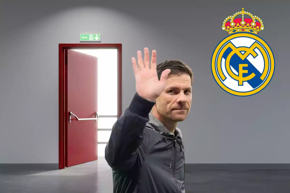 Hombre saludando con la mano frente a una puerta de salida abierta y el escudo del Real Madrid en la pared