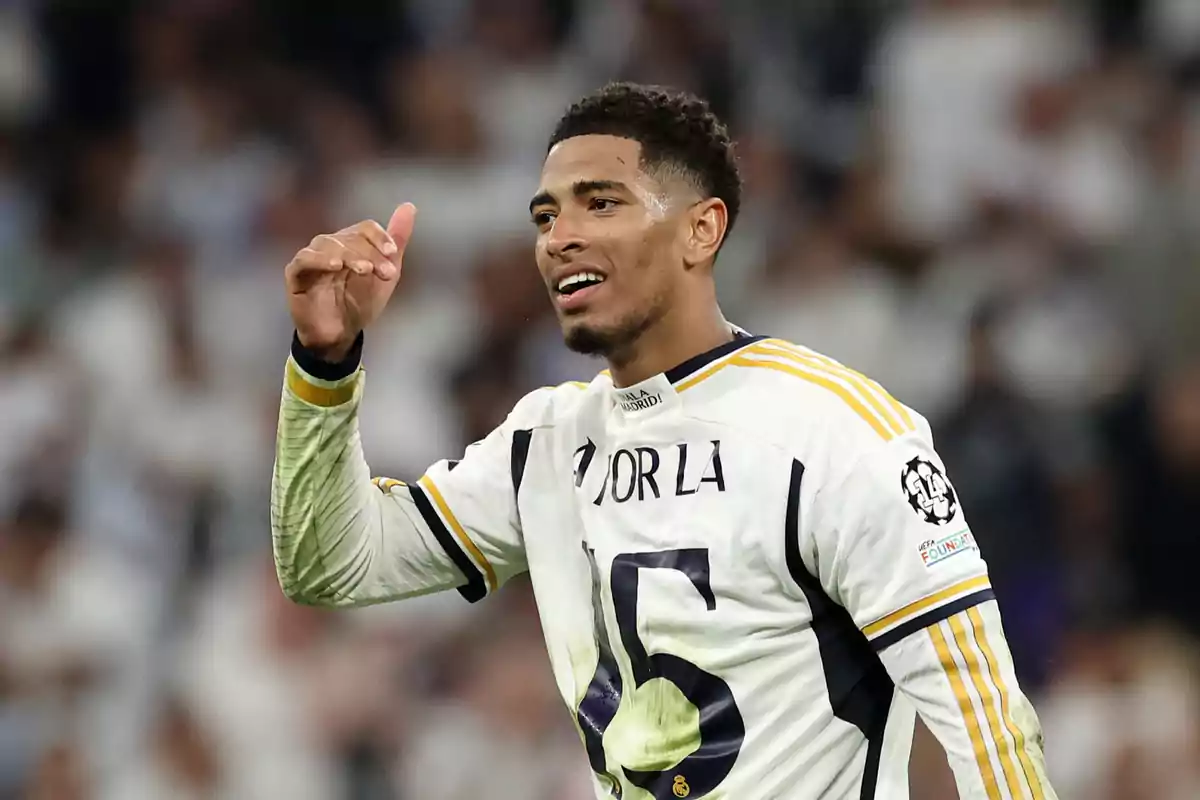 Jugador de fútbol con uniforme blanco celebrando en el campo.