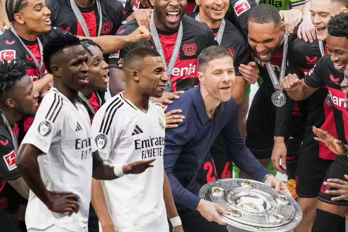 Un grupo de jugadores de fútbol celebra con un trofeo mientras dos jugadores con uniformes blancos están en primer plano.