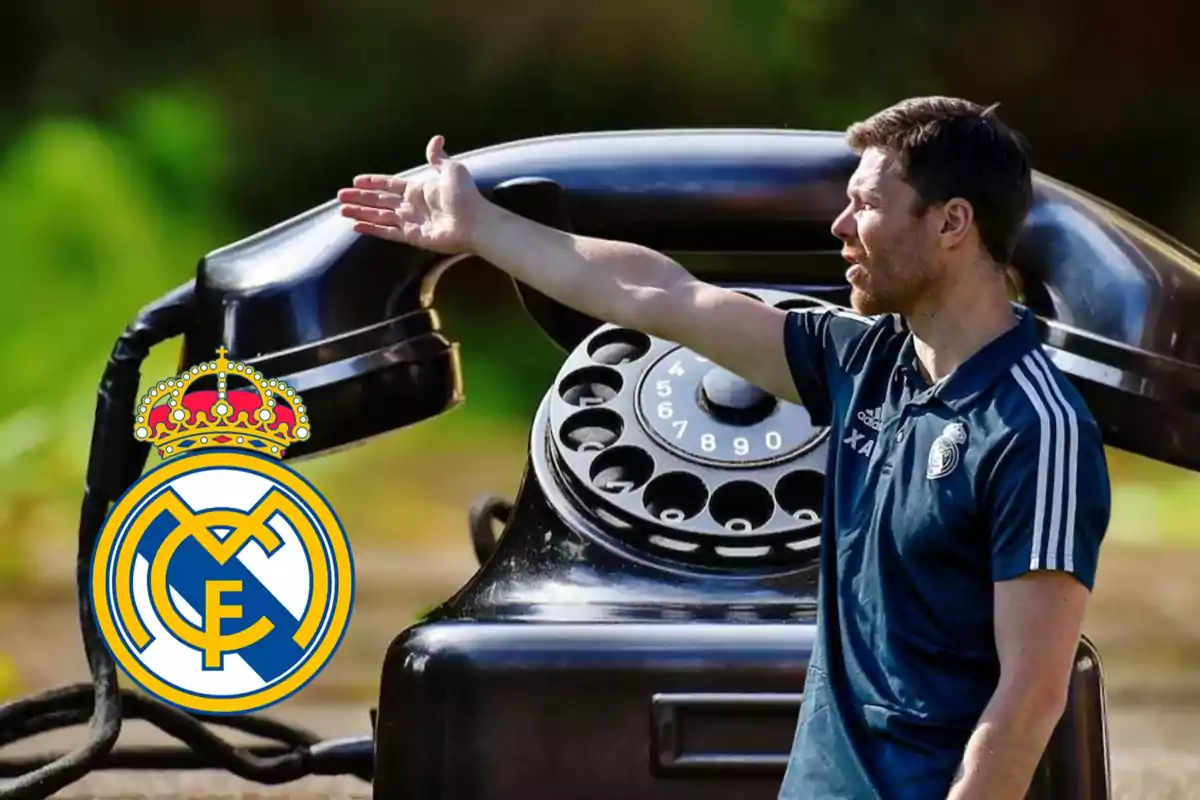 Un entrenador con uniforme del Real Madrid gesticulando frente a un teléfono antiguo de gran tamaño y el escudo del club en primer plano