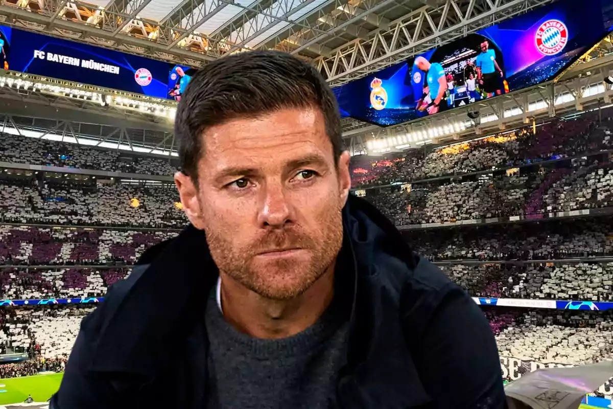 Un hombre en un estadio de fútbol con pantallas mostrando un partido entre el Bayern Múnich y otro equipo.