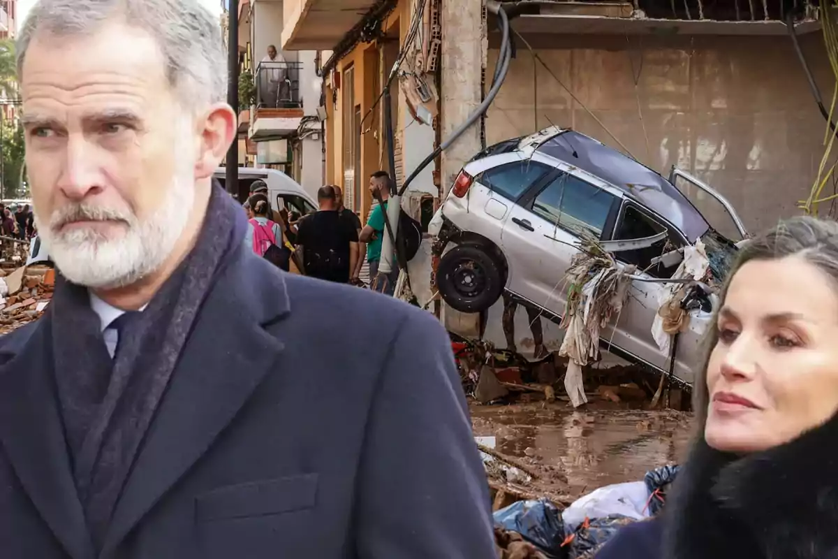 Una escena de desastre con un coche dañado y personas observando, mientras dos personas en primer plano miran hacia adelante.