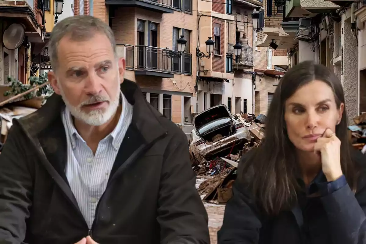 Dos personas sentadas frente a un fondo de una calle con escombros y un coche dañado.