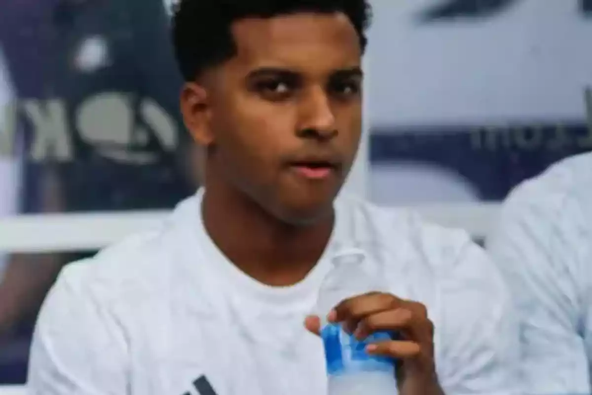 Persona con camiseta blanca sosteniendo una botella de agua.