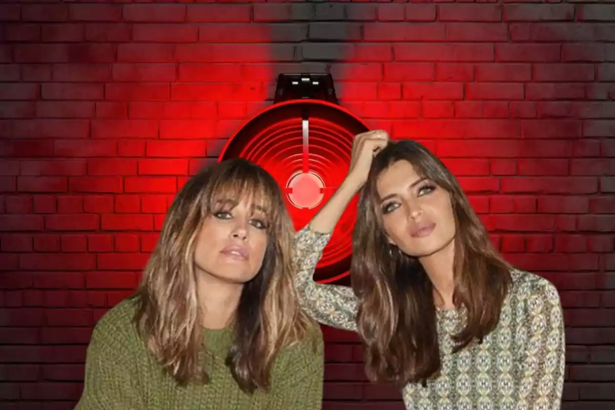 Dos mujeres posando frente a una pared de ladrillos rojos iluminada con una luz roja circular.