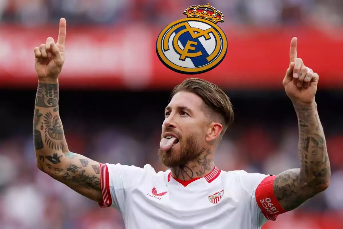 Un jugador de fútbol con la camiseta del Sevilla FC celebrando con los brazos levantados y la lengua afuera, con el escudo del Real Madrid sobre su cabeza.