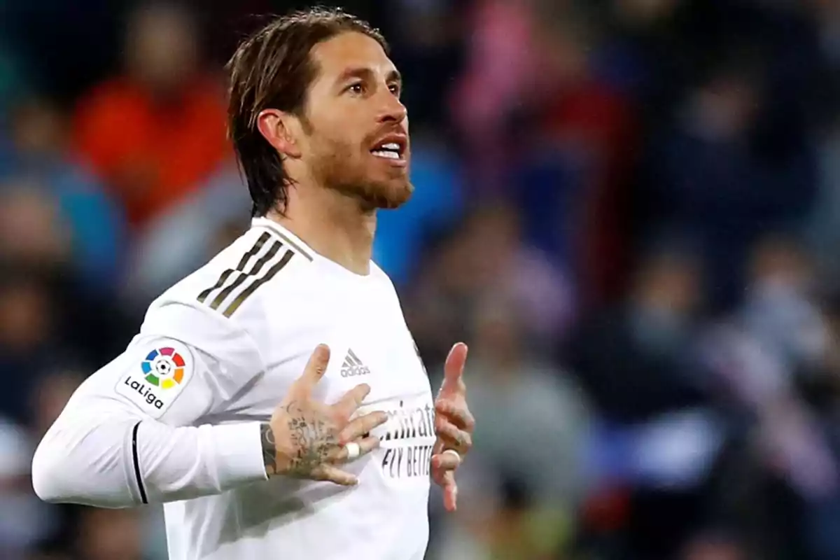 Un jugador de fútbol con uniforme blanco celebrando en el campo.