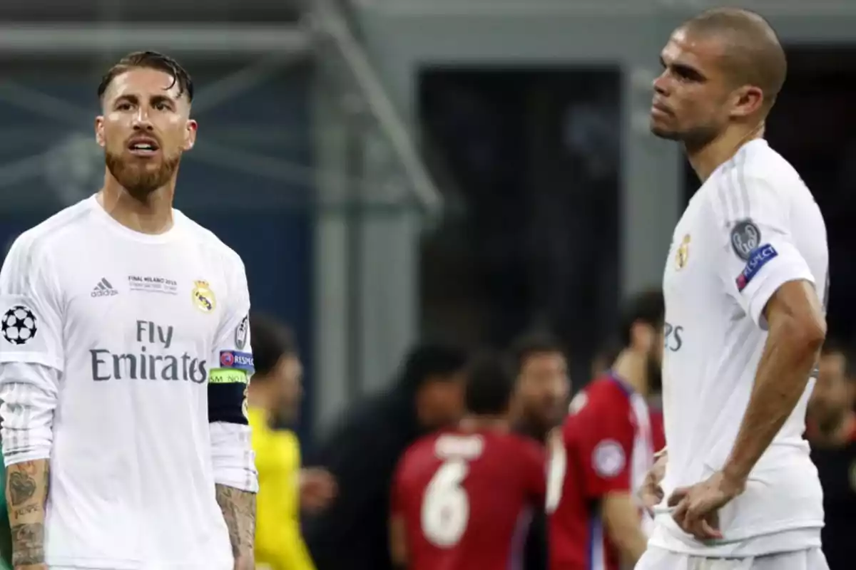 Dos jugadores de fútbol del Real Madrid con uniformes blancos durante un partido, uno de ellos con expresión seria y el otro con expresión pensativa.