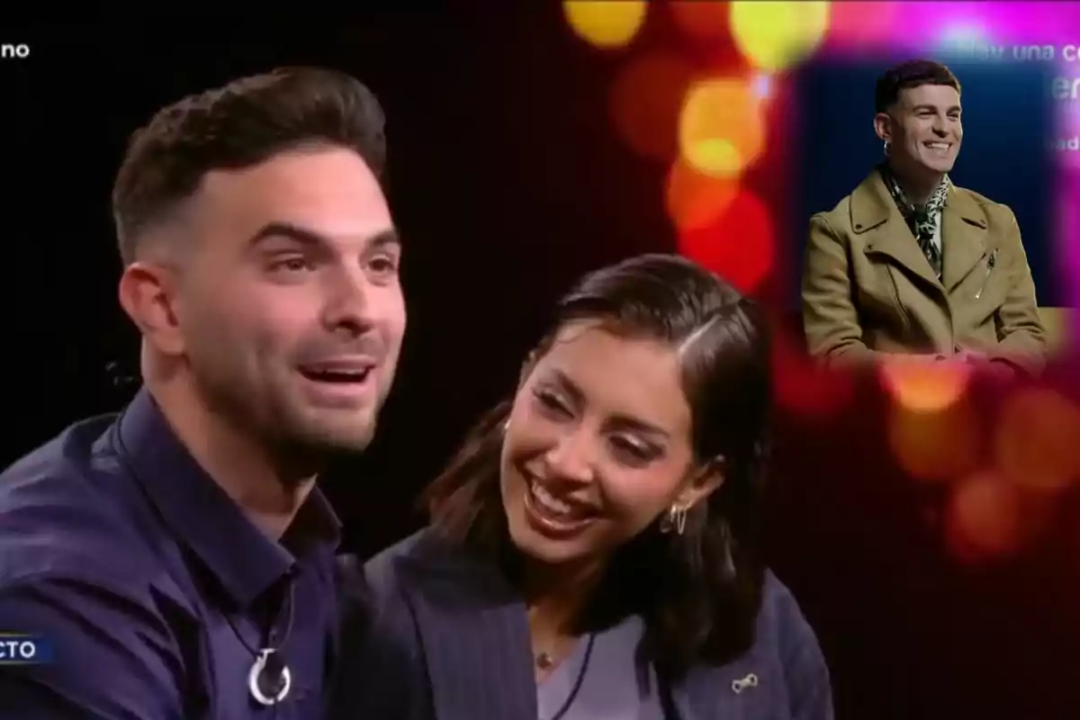 Una pareja sonriente está sentada en un estudio de televisión con luces de fondo desenfocadas y una imagen insertada de un hombre sonriendo con un abrigo marrón.