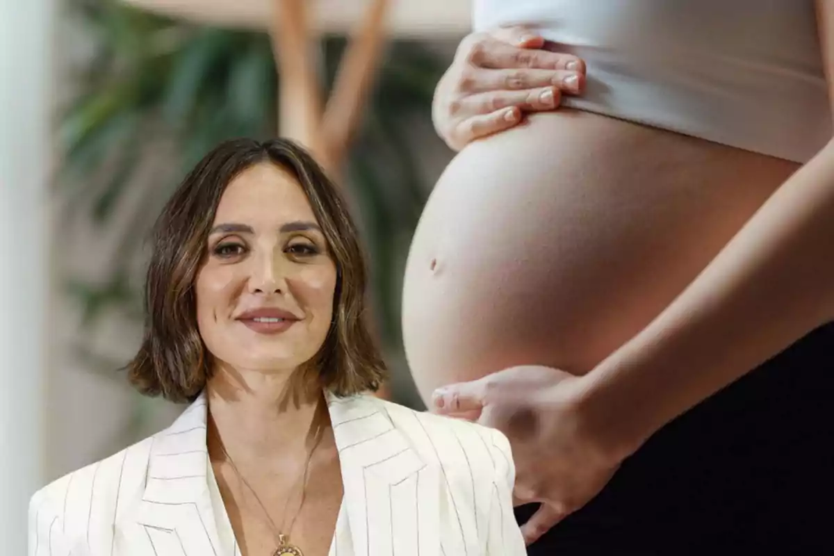 Una mujer con cabello corto y castaño claro, vestida con un blazer blanco, está frente a una imagen de una mujer embarazada que se toca el vientre.