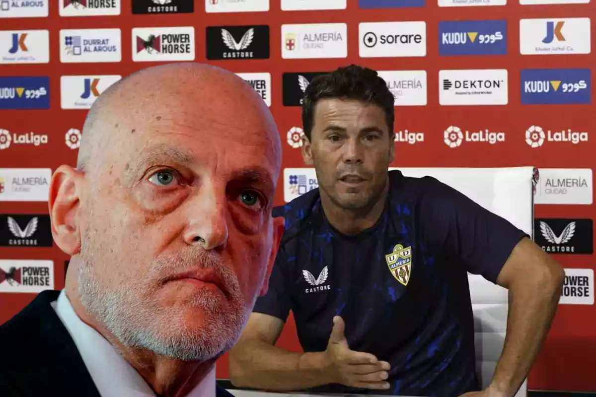 Primer plano de un hombre calvo y serio en traje junto a un entrenador del UD Almería sentado en una rueda de prensa con fondo de patrocinadores deportivos
