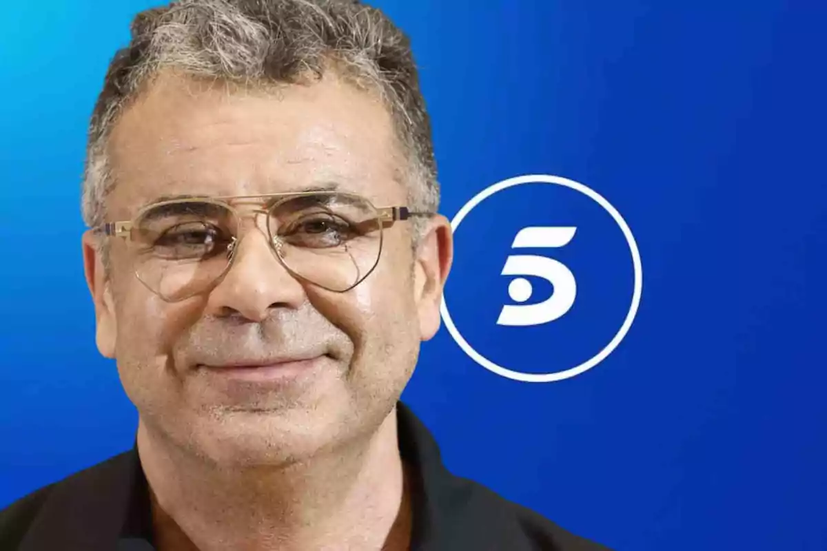 Hombre con gafas frente a un fondo azul con el logotipo de un canal de televisión.