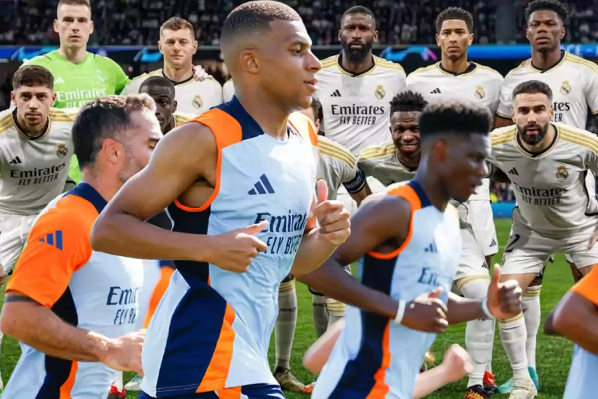 Jugadores de fútbol en uniforme de entrenamiento corren en primer plano, mientras que en el fondo se ve a un equipo de fútbol posando para una foto grupal en el campo.