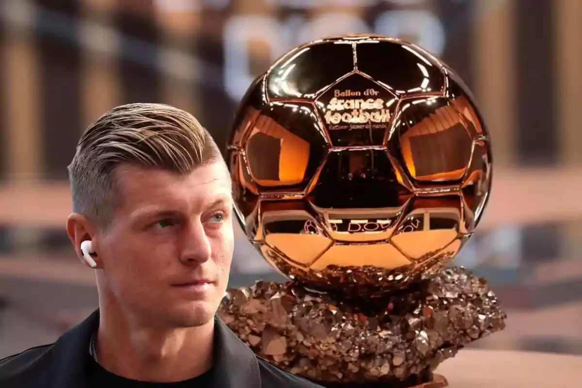 Un hombre con auriculares junto a un trofeo dorado en forma de balón.