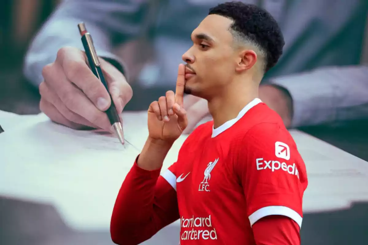 Un jugador de fútbol con el uniforme del Liverpool hace un gesto de silencio con el dedo frente a una imagen de fondo de una mano escribiendo con un bolígrafo.