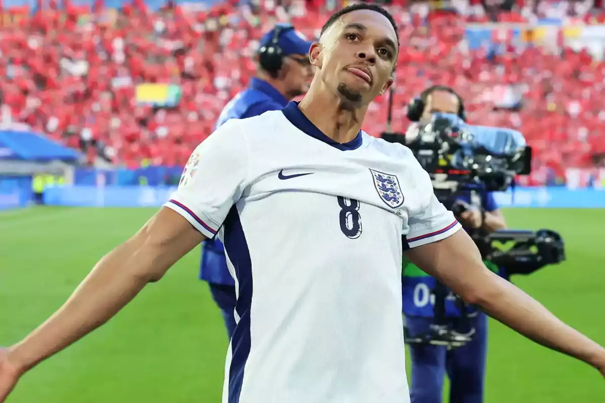 Jugador de fútbol con la camiseta de Inglaterra celebrando en el campo con una multitud de fondo.