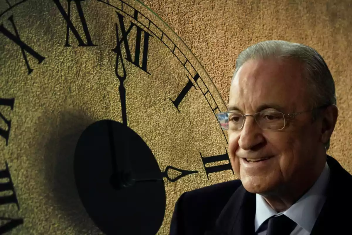 Un hombre mayor con gafas y cabello canoso sonriendo frente a un reloj antiguo con números romanos.