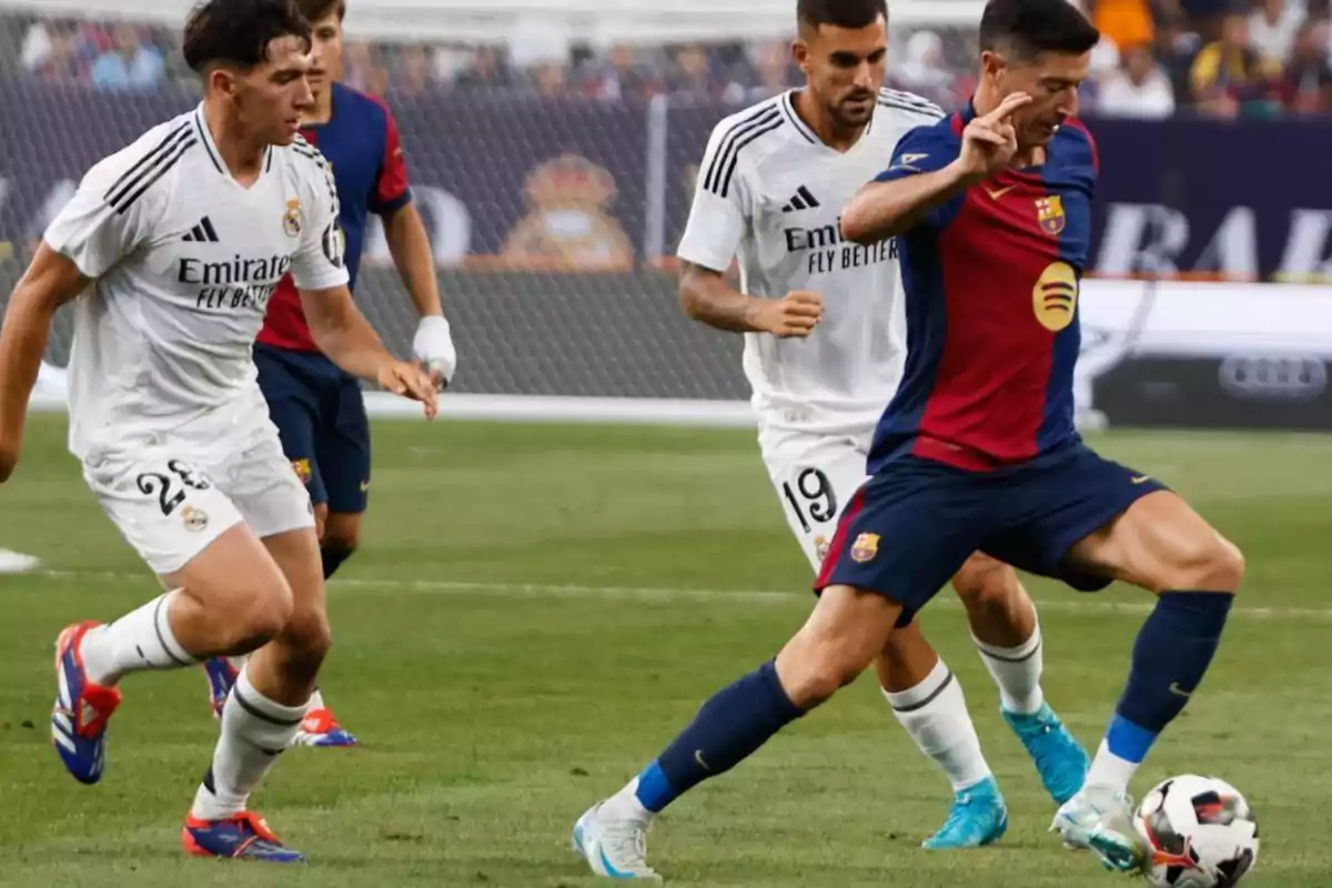 Jugadores de fútbol de los equipos Real Madrid y Barcelona compiten por el balón en un partido.