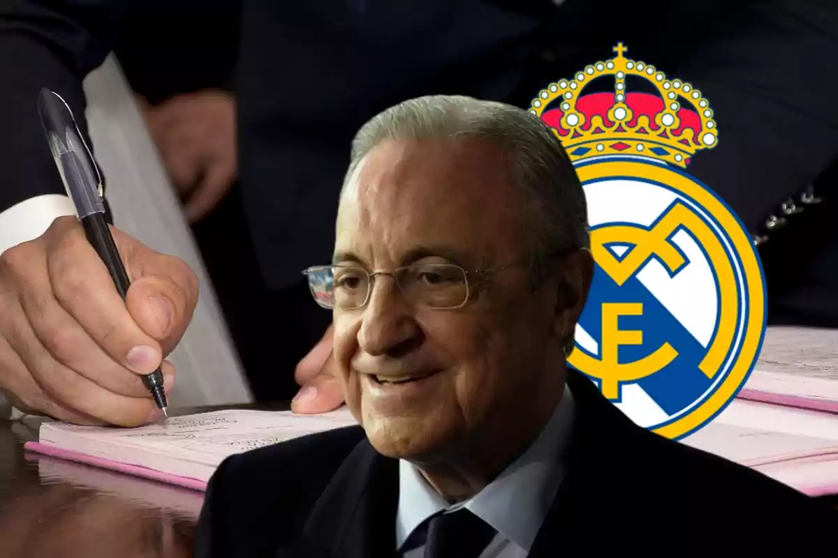 Un hombre mayor con gafas sonríe frente al escudo del Real Madrid mientras una mano sostiene un bolígrafo y firma un documento.