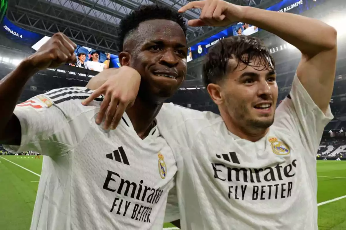 Dos jugadores de fútbol del Real Madrid celebrando en el campo con camisetas blancas.