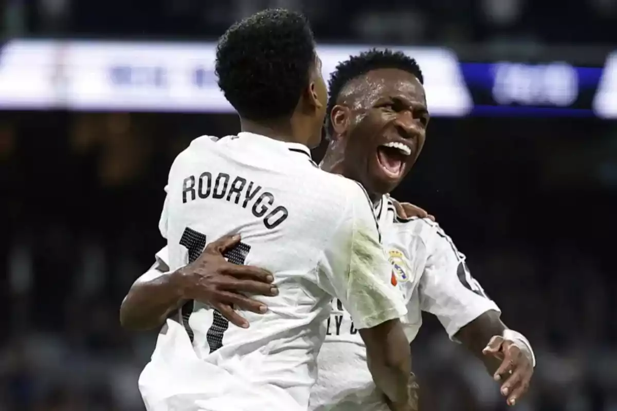 Dos jugadores de fútbol celebrando un gol con entusiasmo en el campo.