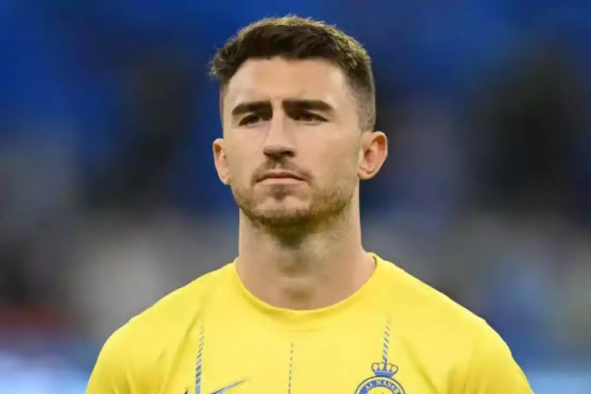 Un jugador de fútbol con camiseta amarilla en un estadio.