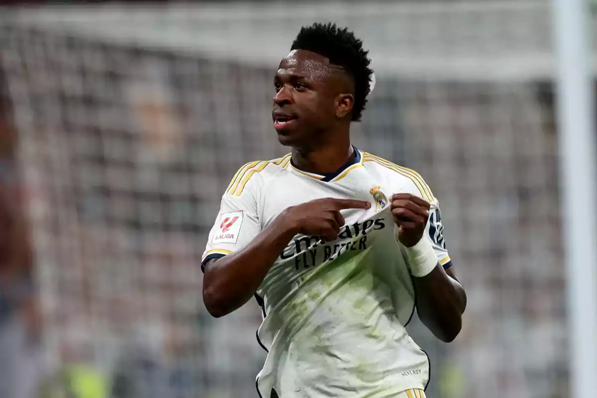 Jugador de fútbol señalando el escudo de su camiseta durante un partido.