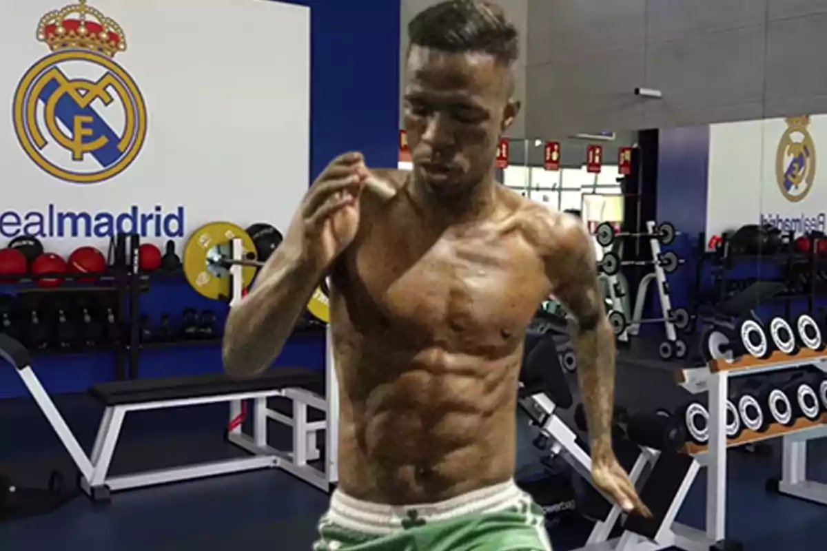 Un hombre musculoso entrenando en un gimnasio con el logo del Real Madrid en la pared.